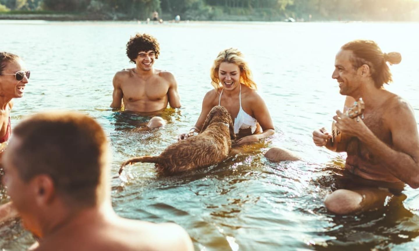 Grupo de amigos disfrutando de actividades acuáticas con un perro en Les Chalets Du Lac, Montréjeau