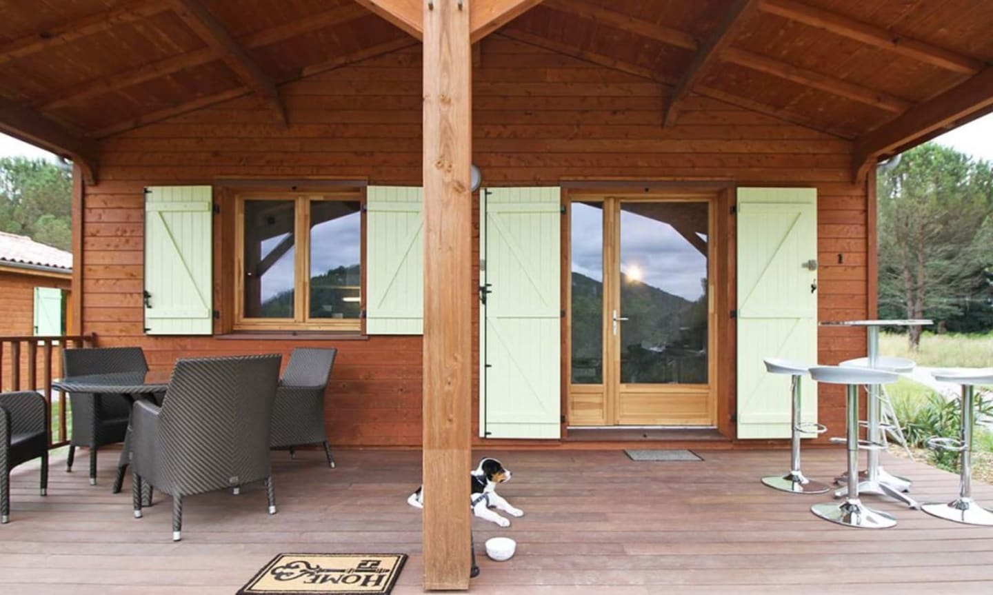Chalet en bois avec terrasse couverte, mobilier extérieur et vue sur les montagnes aux Chalets Du Lac à Clarac, France.