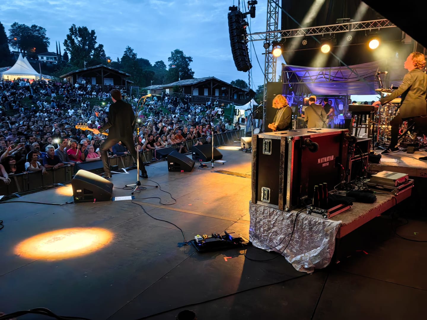 Scène de concert en plein air aux Chalets Du Lac De Montréjeau avec foule et équipements d'éclairage au crépuscule