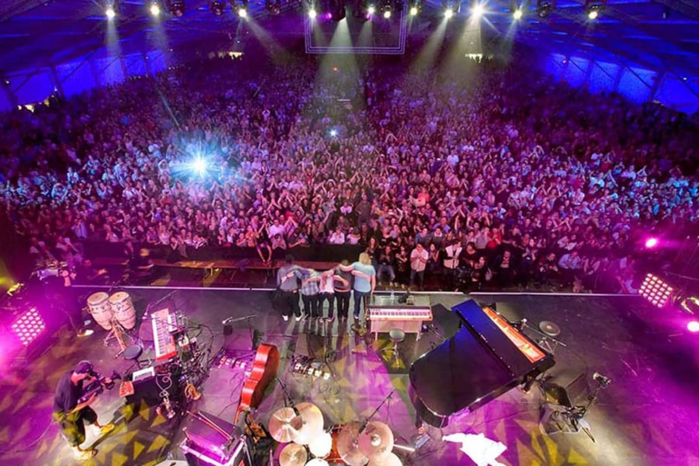 Grand lieu de concert avec des milliers de spectateurs, éclairage scénique coloré et groupe jouant en direct près de Clarac