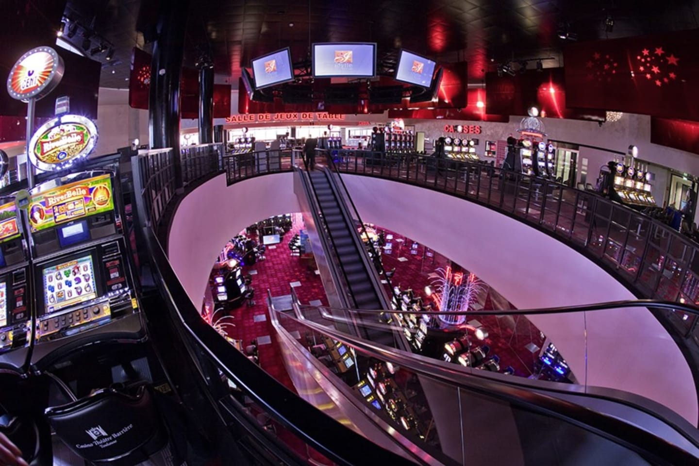 Sala de casino con máquinas tragaperras, escaleras mecánicas e iluminación roja en Les Chalets Du Lac, Clarac