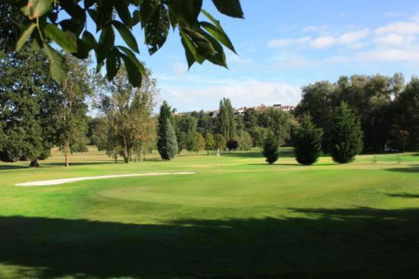 Parcours de golf pittoresque aux Chalets Du Lac De Montréjeau à Clarac avec fairways impeccables, grands arbres et ciel bleu