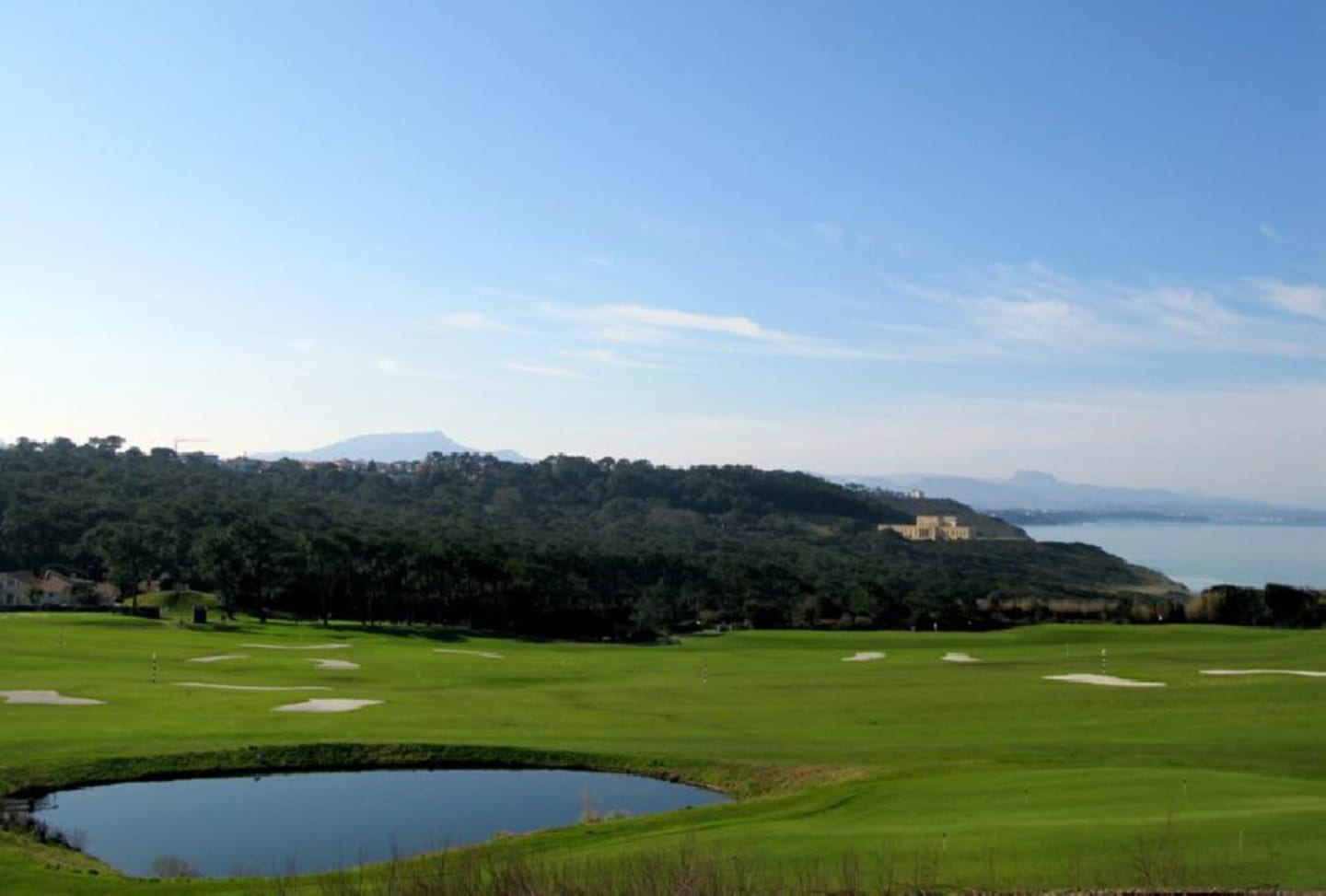 Lush golf course at Les Chalets Du Lac De Montréjeau in Clarac with pond, mountains, and lake views