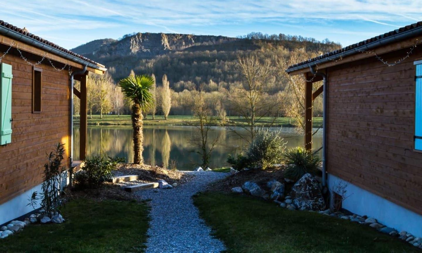 Cour des Chalets Du Lac avec allée gravillonnée, vue sur le lac, montagnes et palmiers à Clarac