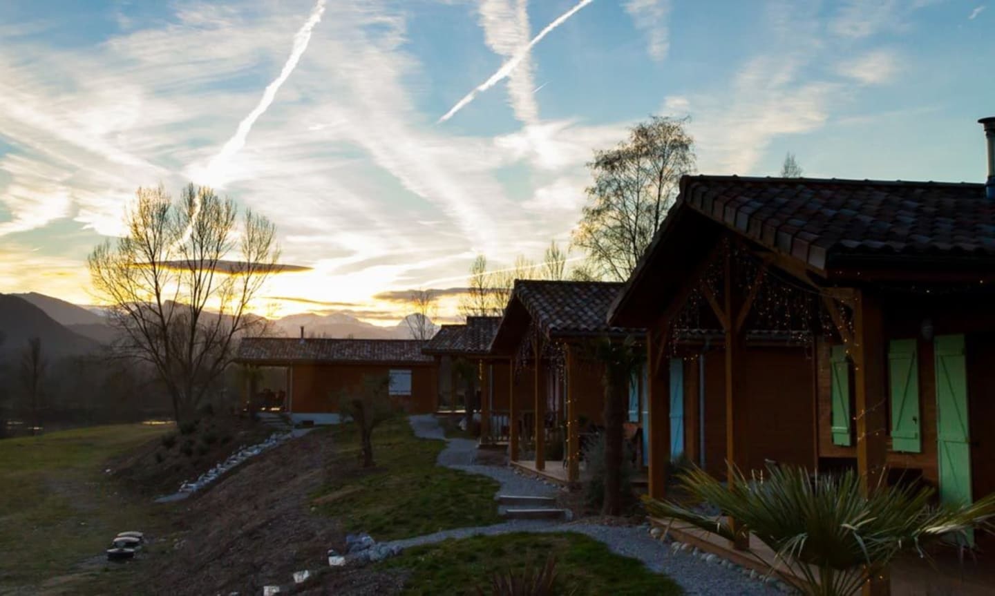 Chalets en bois aux Chalets Du Lac De Montréjeau à Clarac au coucher de soleil avec montagnes et sapins