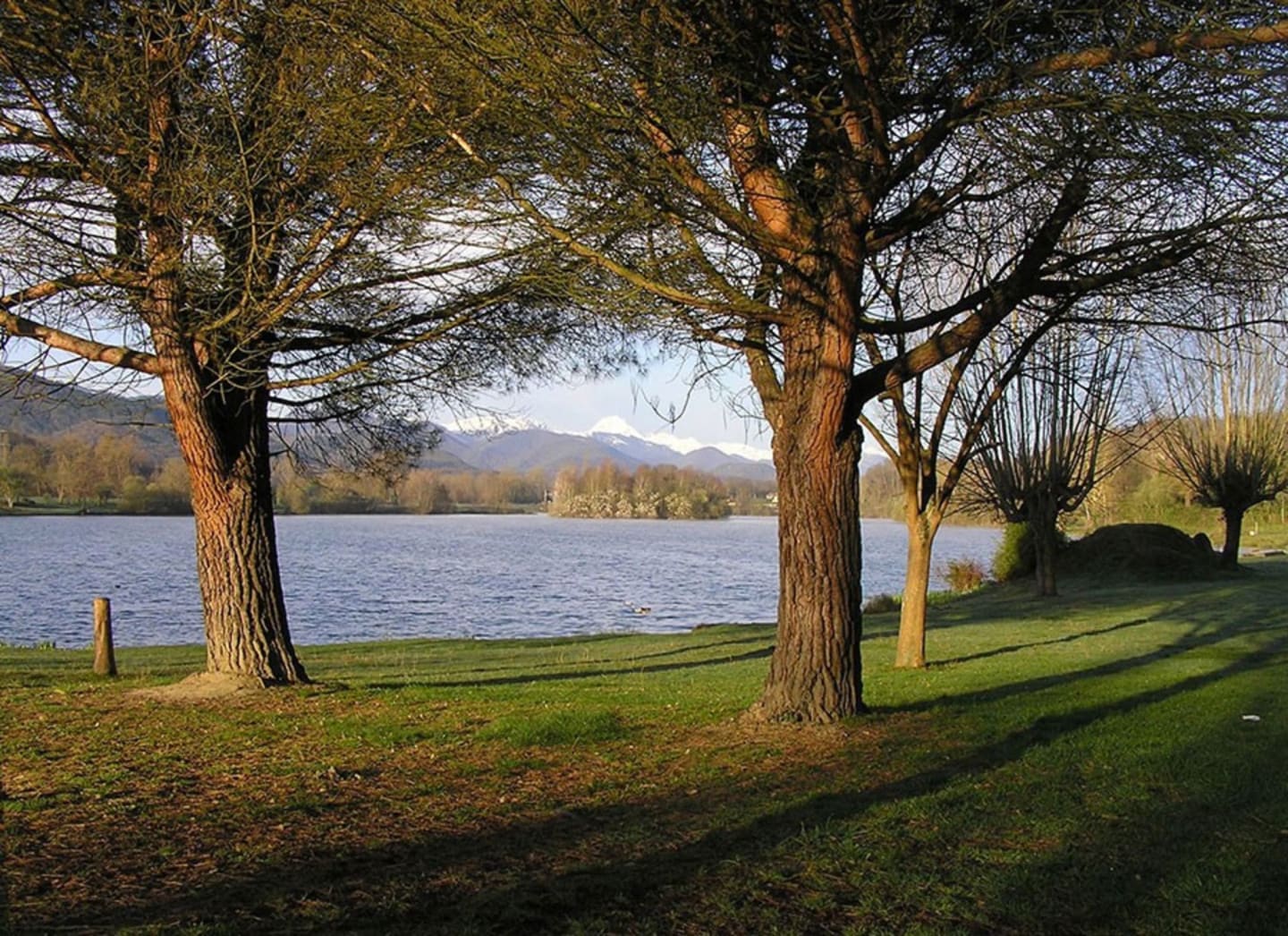 Parc au bord du lac avec arbres matures encadrant la vue sur les montagnes aux Chalets Du Lac De Montréjeau à Clarac, France