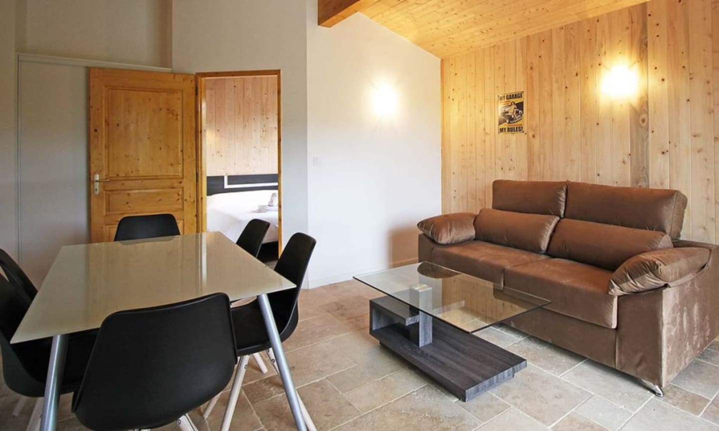 Salon moderne avec canapé marron, table à manger et murs en bois de pin aux Chalets Du Lac De Montréjeau, Clarac