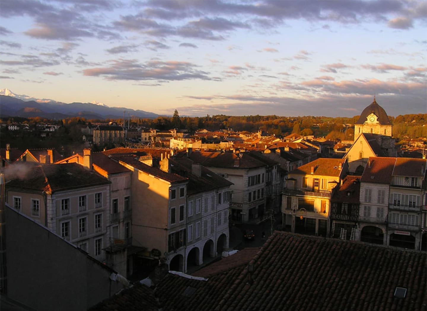Puesta de sol dorada sobre el paisaje de Clarac con edificios históricos y campanario