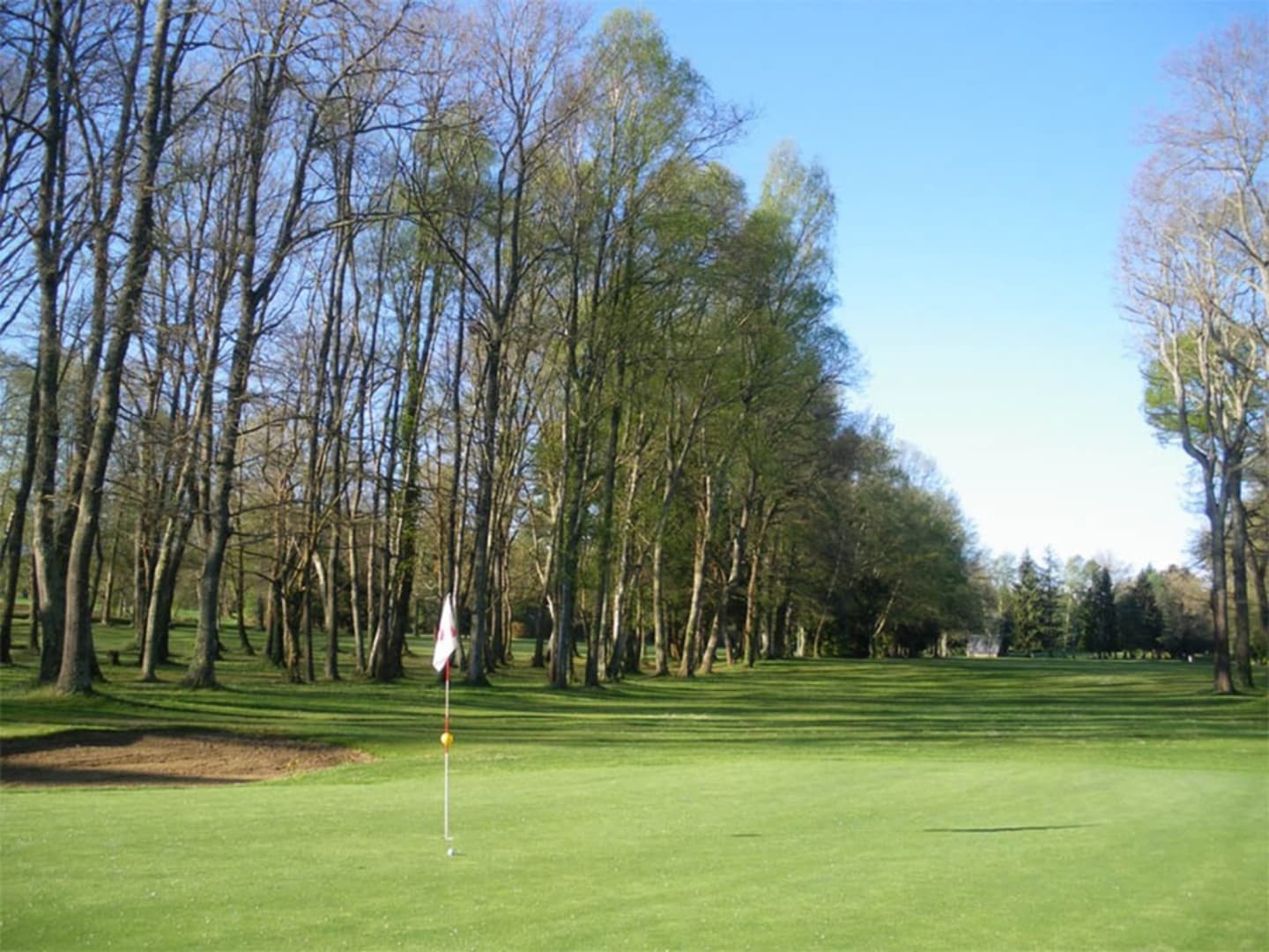 Golf course at Les Chalets Du Lac De Montréjeau with lined trees and flag, Clarac France