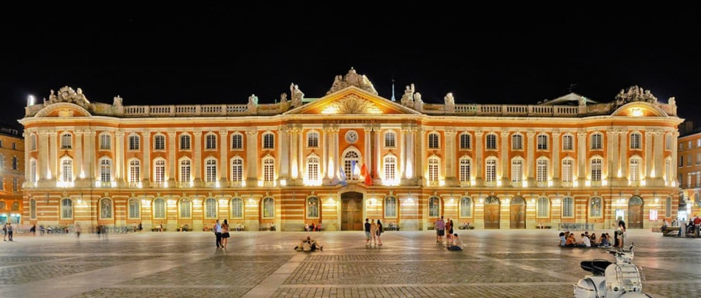 Bâtiment néoclassique doré et orné illuminé la nuit sur une place de ville française près de Clarac