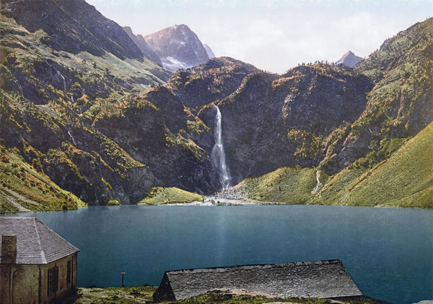 Lac alpin avec cascade, pics montagneux et chalets au Lac de Montréjeau, Clarac France