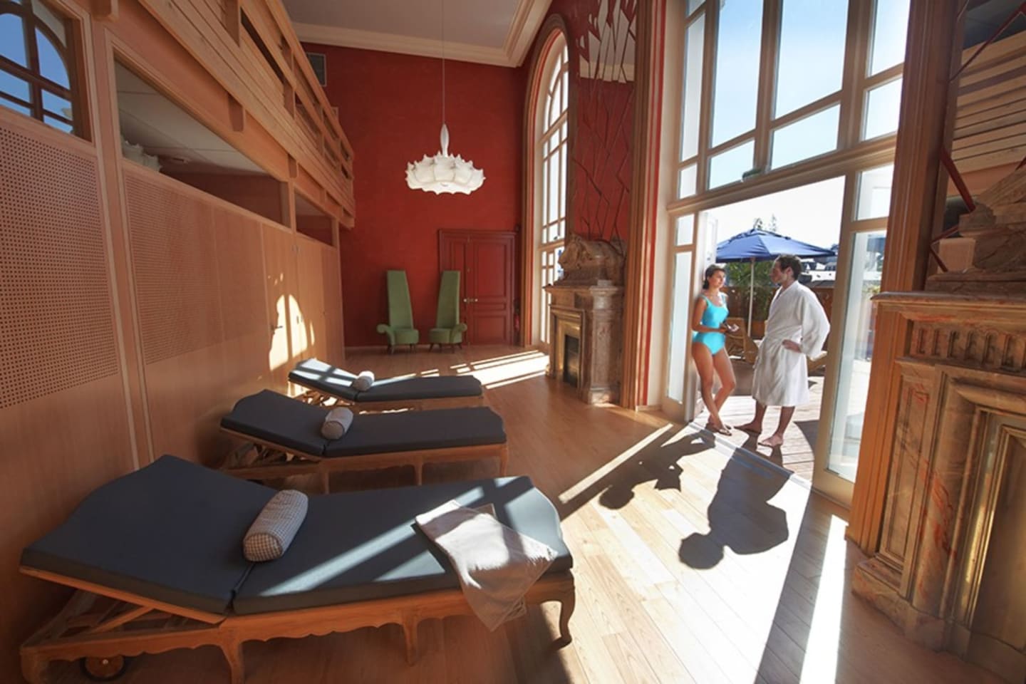 Modern spa room at Les Chalets Du Lac De Montréjeau with massage beds, red walls, and terrace view in Clarac.