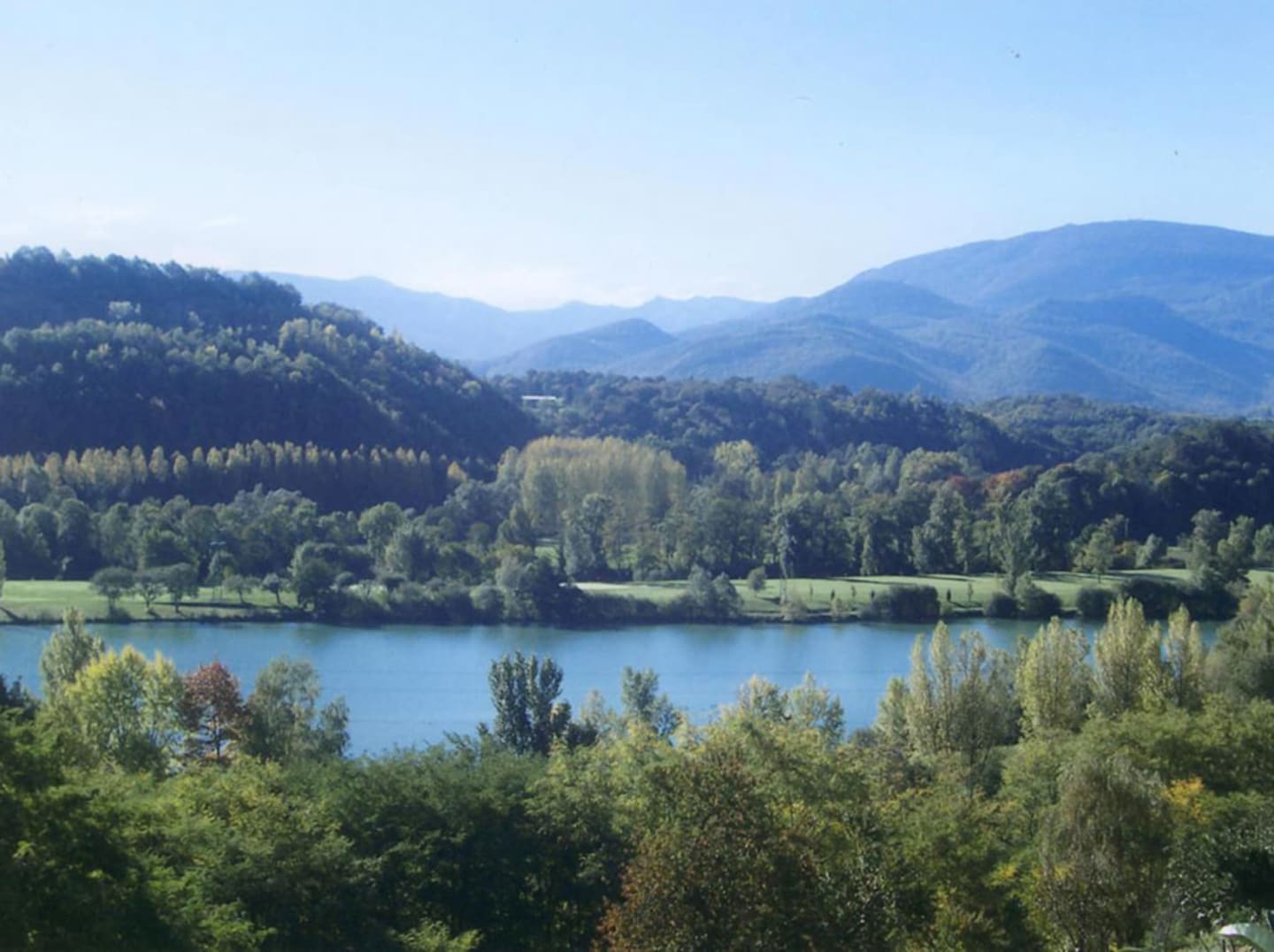 Vue panoramique du lac entouré de forêts et montagnes près des Chalets Du Lac, Clarac, France