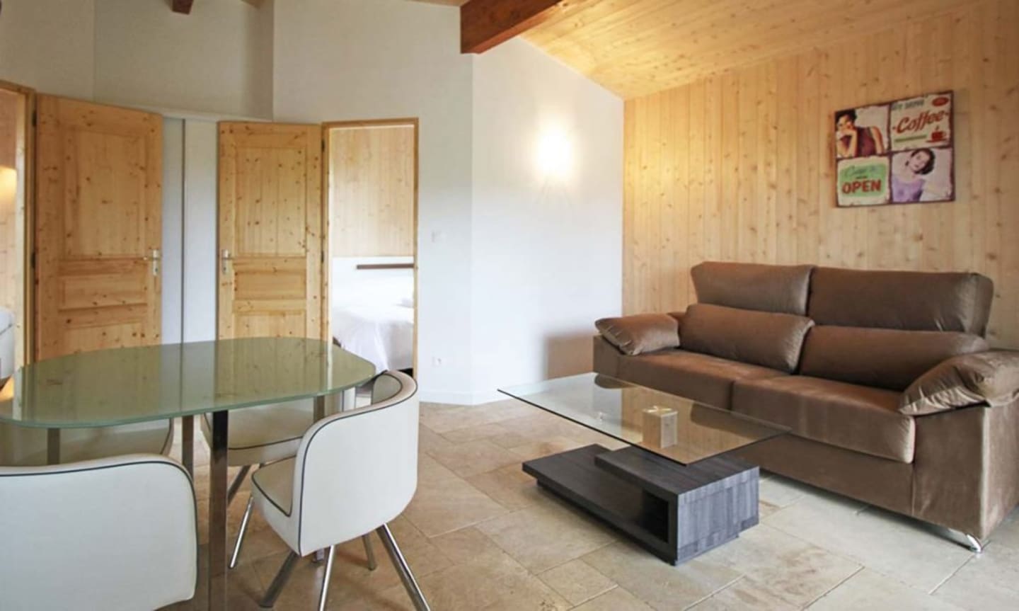 Studio moderne avec canapé marron, table à manger, armoire en bois et murs en pin aux Chalets Du Lac