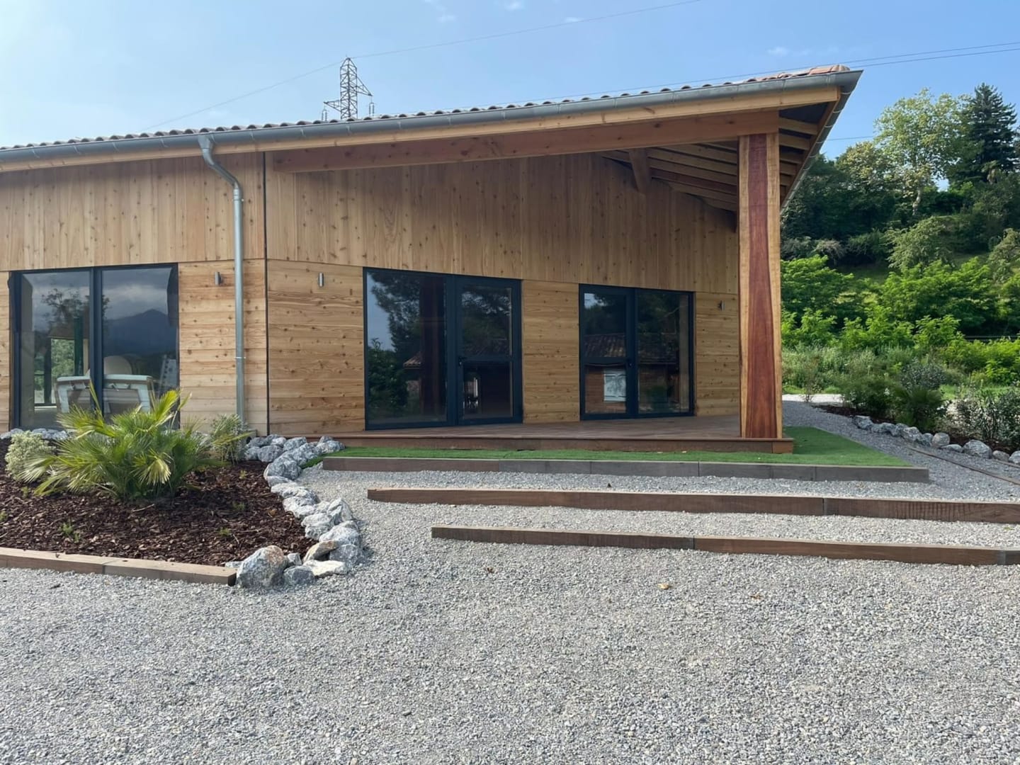 Chalet moderne en bois avec grandes fenêtres et véranda couverte aux Chalets Du Lac De Montréjeau à Clarac, France