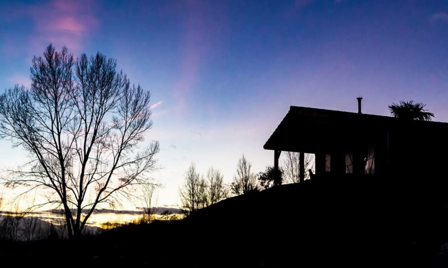 Silhouette de Les Chalets Du Lac au coucher de soleil avec arbres nus et ciel violet près de Clarac, France