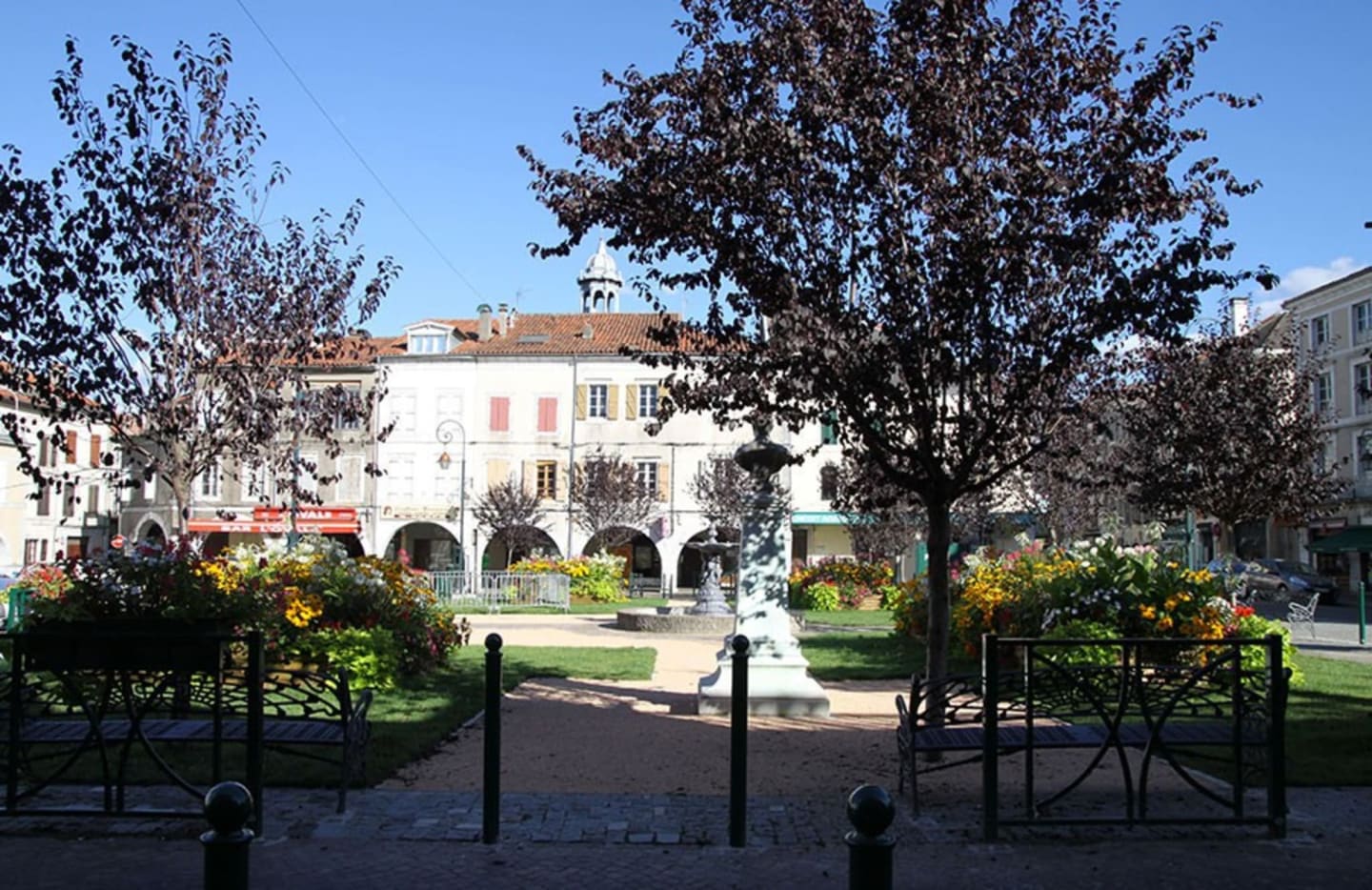 Plaza del pueblo de Clarac con edificio blanco histórico, árboles y áreas verdes cerca de Les Chalets Du Lac