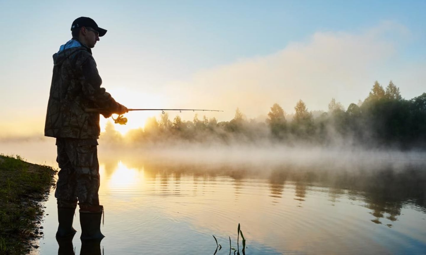 Pescador al amanecer en el lago brumoso cerca de Les Chalets Du Lac De Montréjeau, Clarac Francia