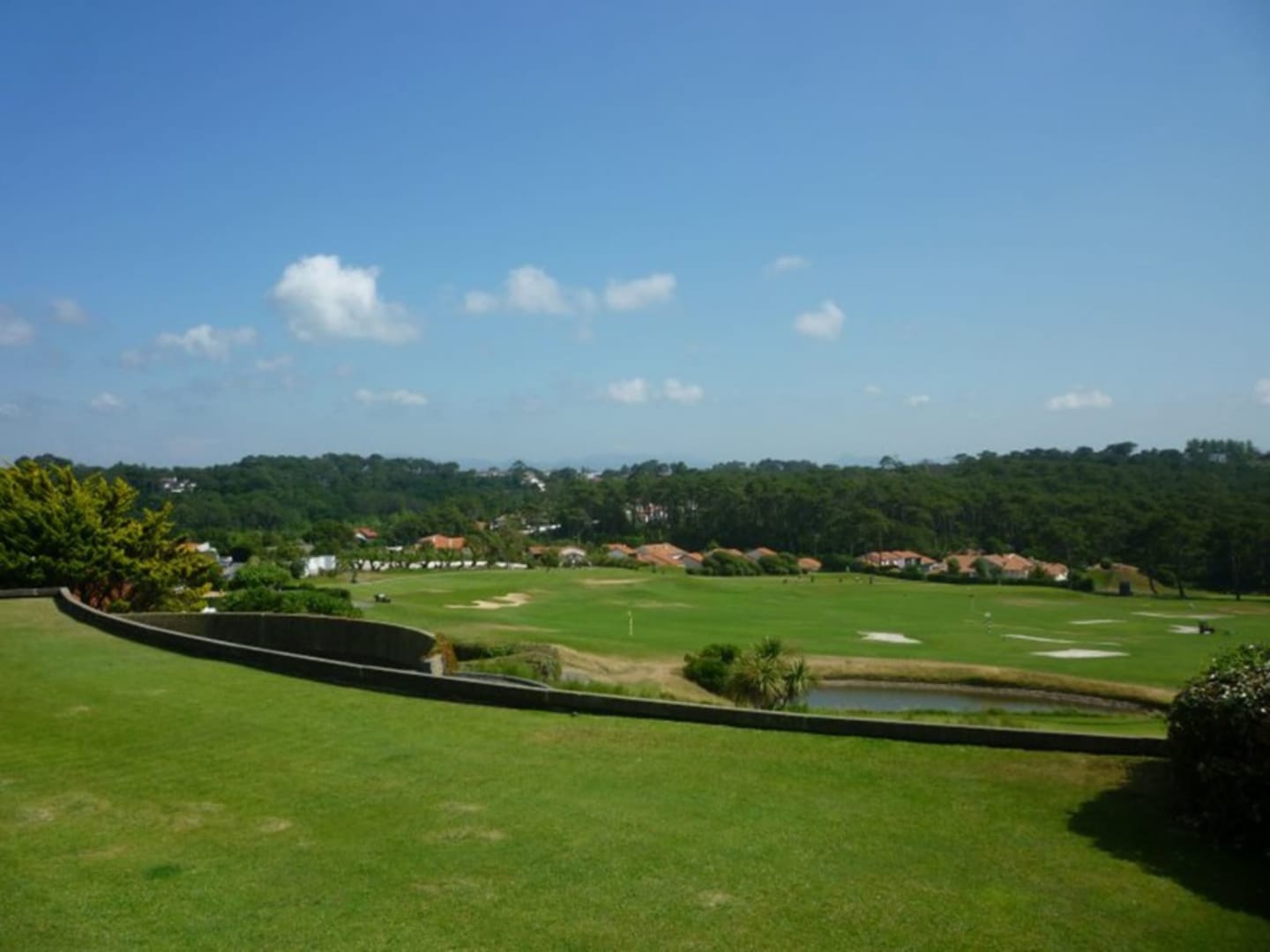 Golf course at Les Chalets Du Lac with green fairways, bunkers, trees and residential homes in Clarac