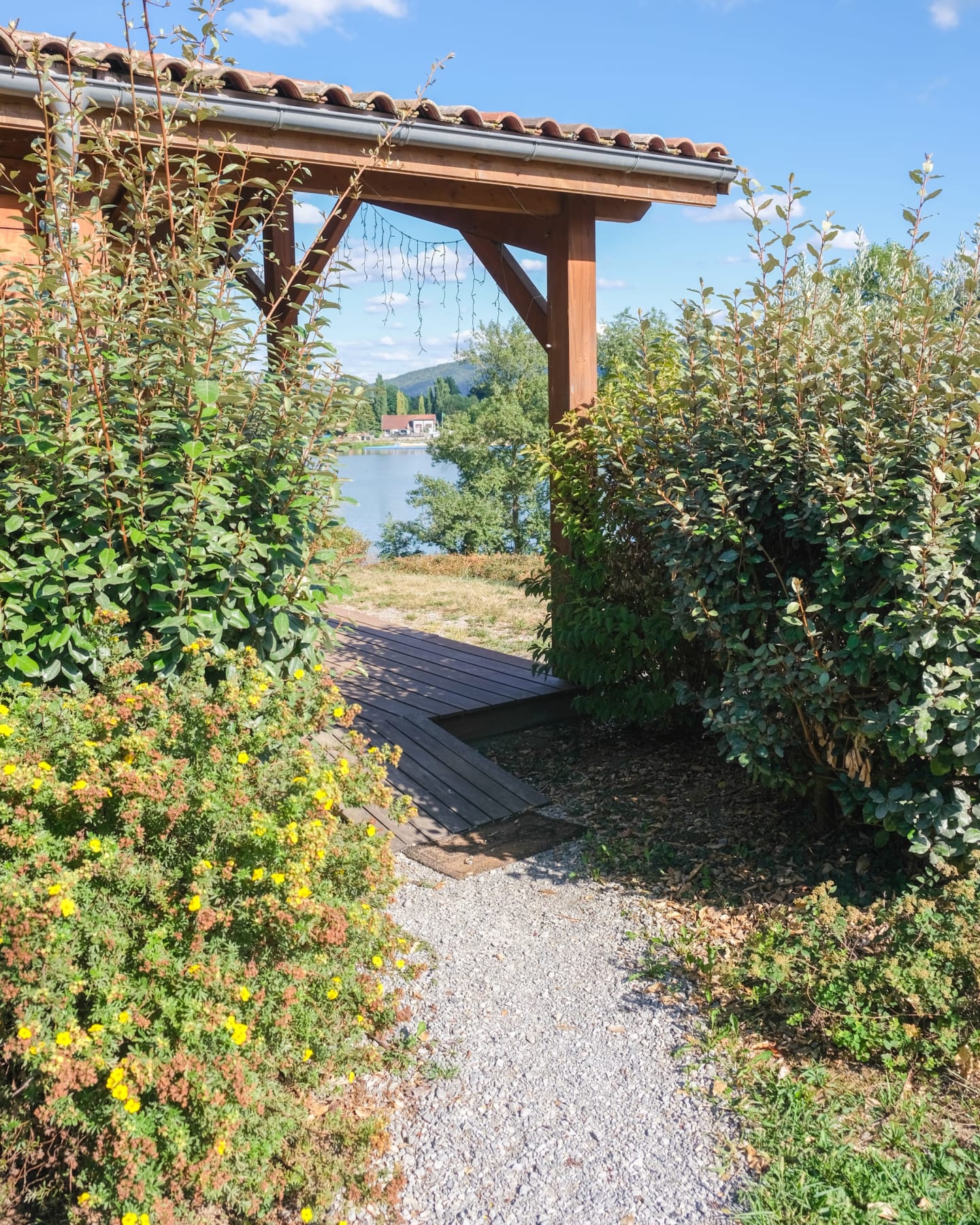 Pergola en bois avec plantes suspendues surplombant le lac aux Chalets Du Lac, Clarac