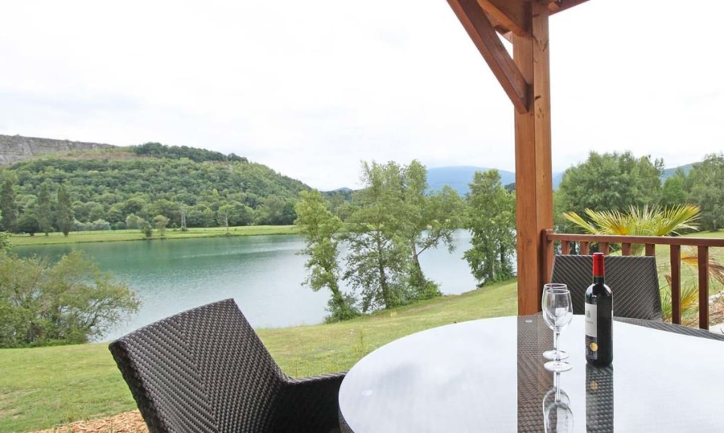 Terrasse au bord du lac aux Chalets Du Lac de Montréjeau avec service de vin et vue panoramique sur l'eau