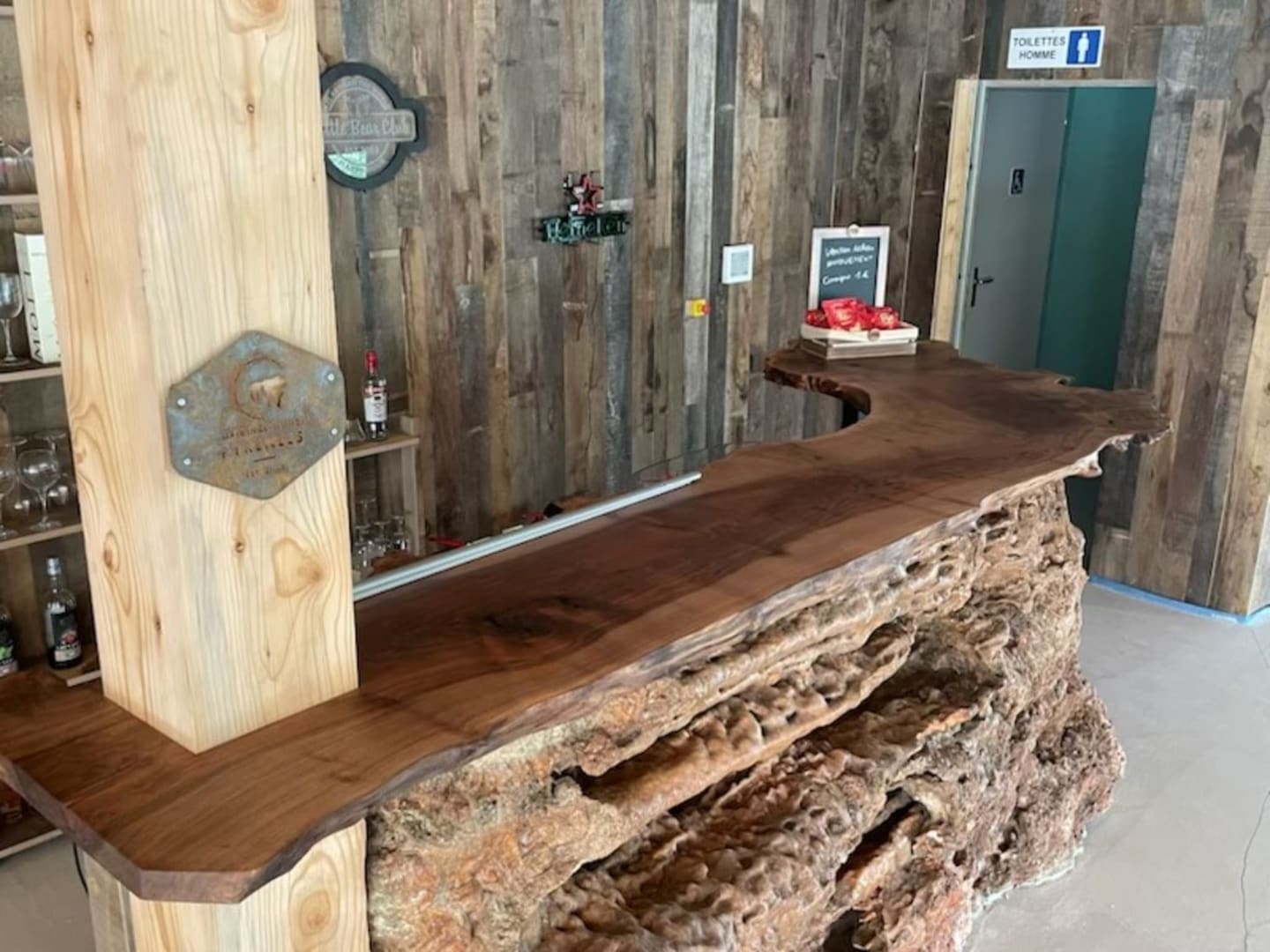 Bar en pierre naturelle de la salle d'événementiel des l'hôtel des Chalets de Montréjeau ayant un plan de travail en bois massif 